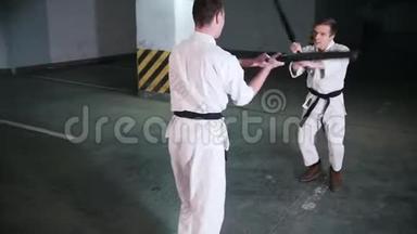 两个人在停车场训练剑道。 剑战